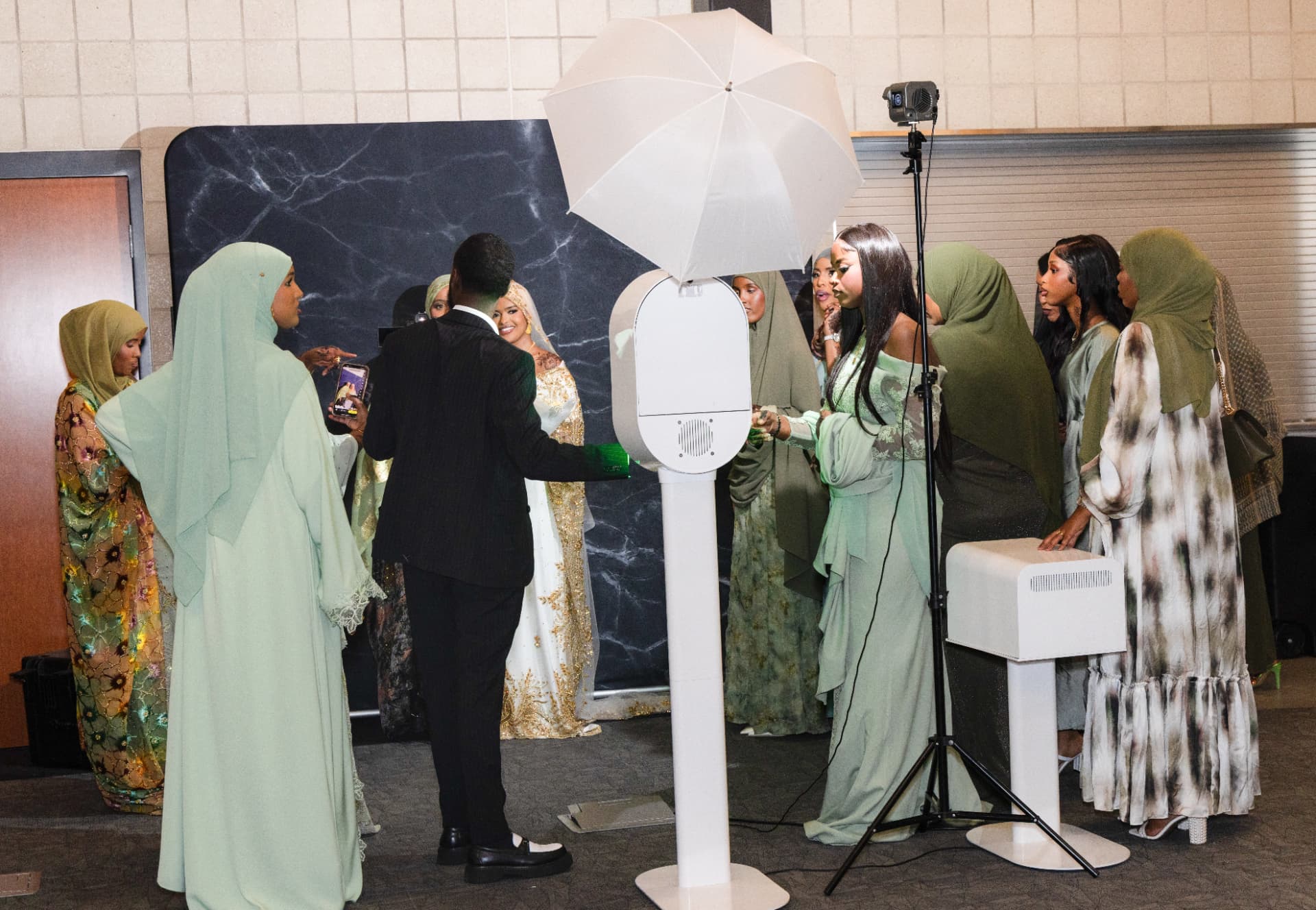 Wedding guests gathered around the Xirfad Studio photo booth with a black marble backdrop
