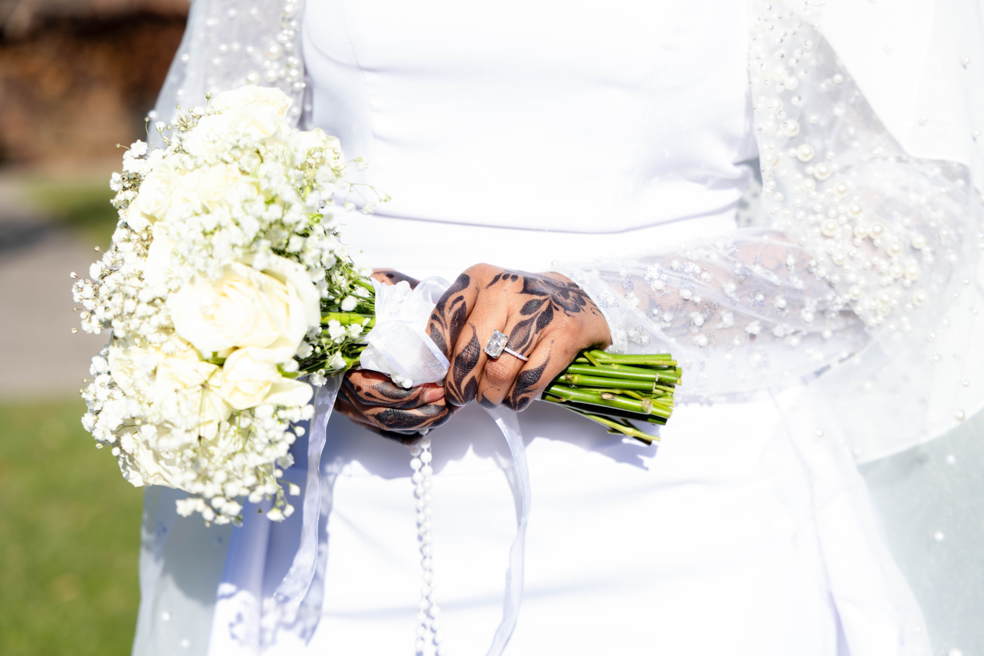 Bride holding a white rose and baby's breath bouquet with henna-adorned hands at a St. Cloud wedding
