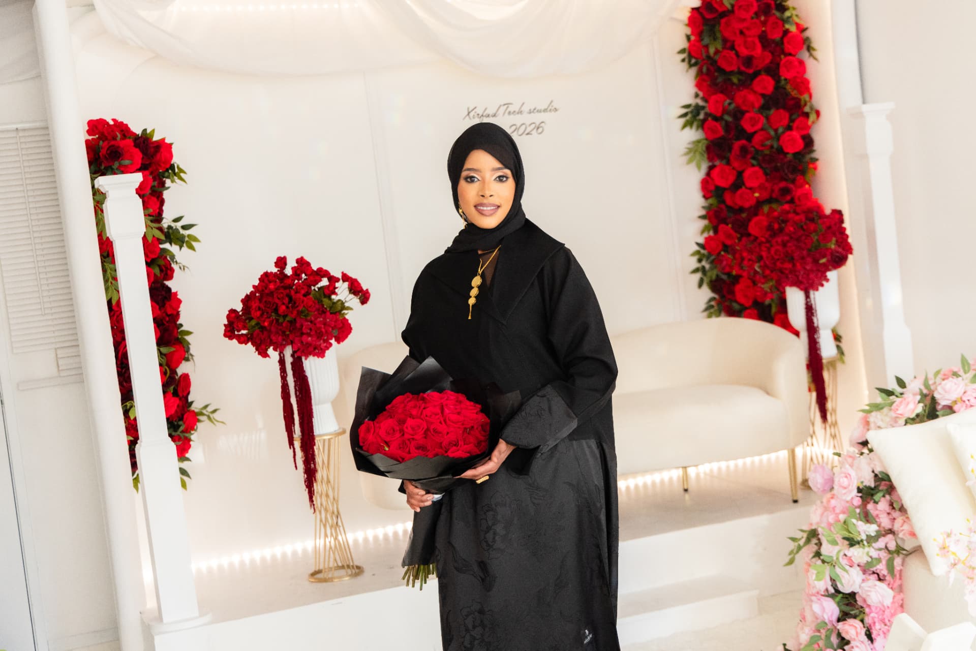 Woman holding red roses in front of the Xirfad Studio rose backdrop